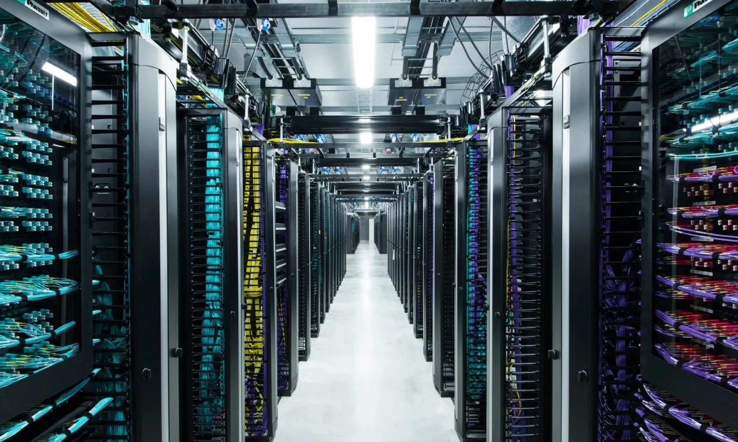 Pasillo del centro de datos de Facebook de Metaplataformas entre filas de racks de servidores e infraestructura de administración de cables