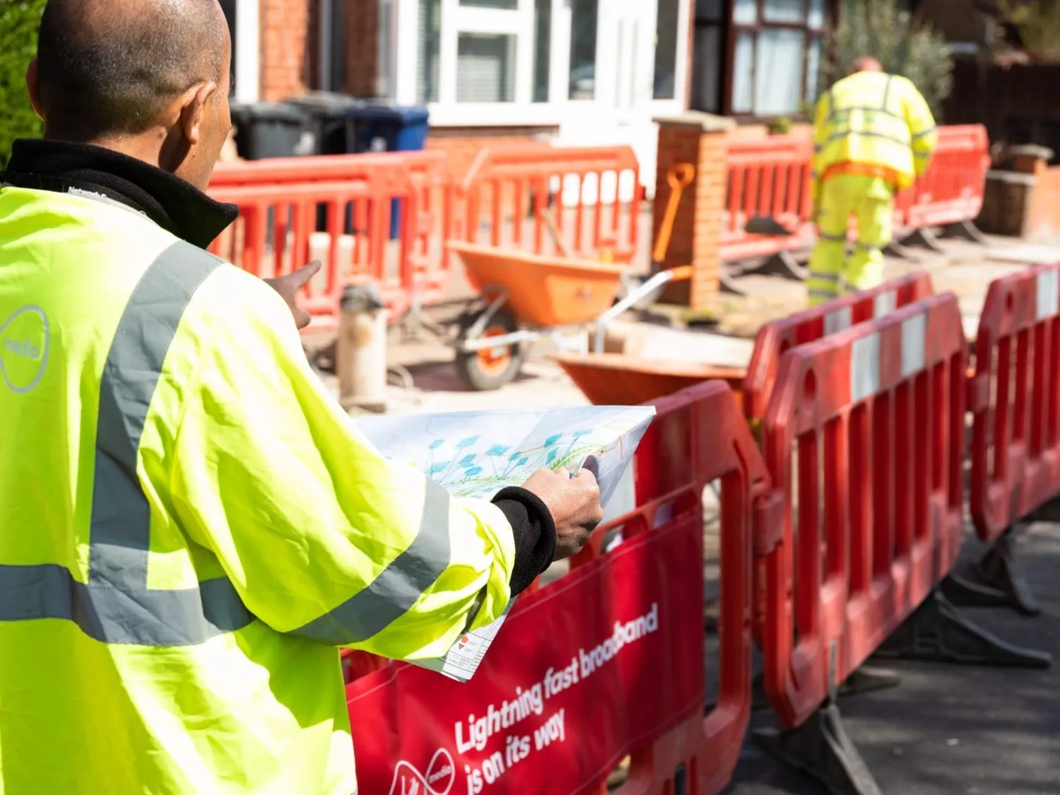Hombre examina los planes de implementación en el sitio de construcción de fibra para Virgin Media O2